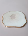 "By Hand Onderzetter Ardha, handgemaakt van epoxy in wit met subtiel glinsterend centrum en gouden rand – uniek interieuraccessoire.