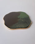 Detail van By Hand Onderzetter Earth, handgemaakt van epoxy in groen en bruin met goudkleurige rand – unieke ambachtelijke onderzetter.