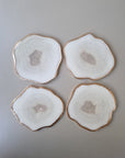 Set van vier By Hand onderzetters Ardha, handgemaakt in epoxy, wit met subtiel glinsterend centrum en gouden rand – unieke interieuraccessoires.