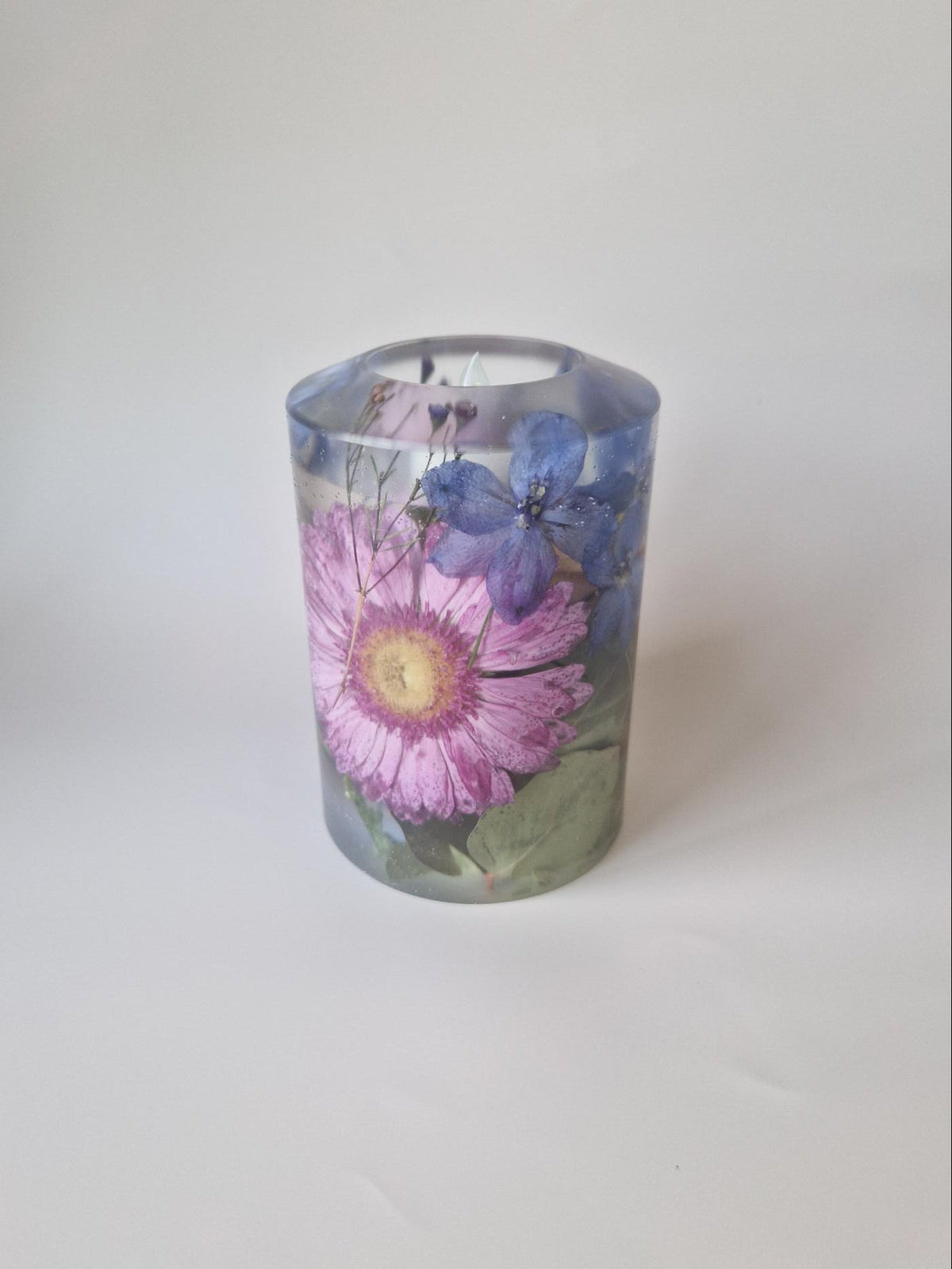 Bruiloft kaars van transparante epoxy met roze en blauwe bewaarde bloemen uit het bruidsboeket