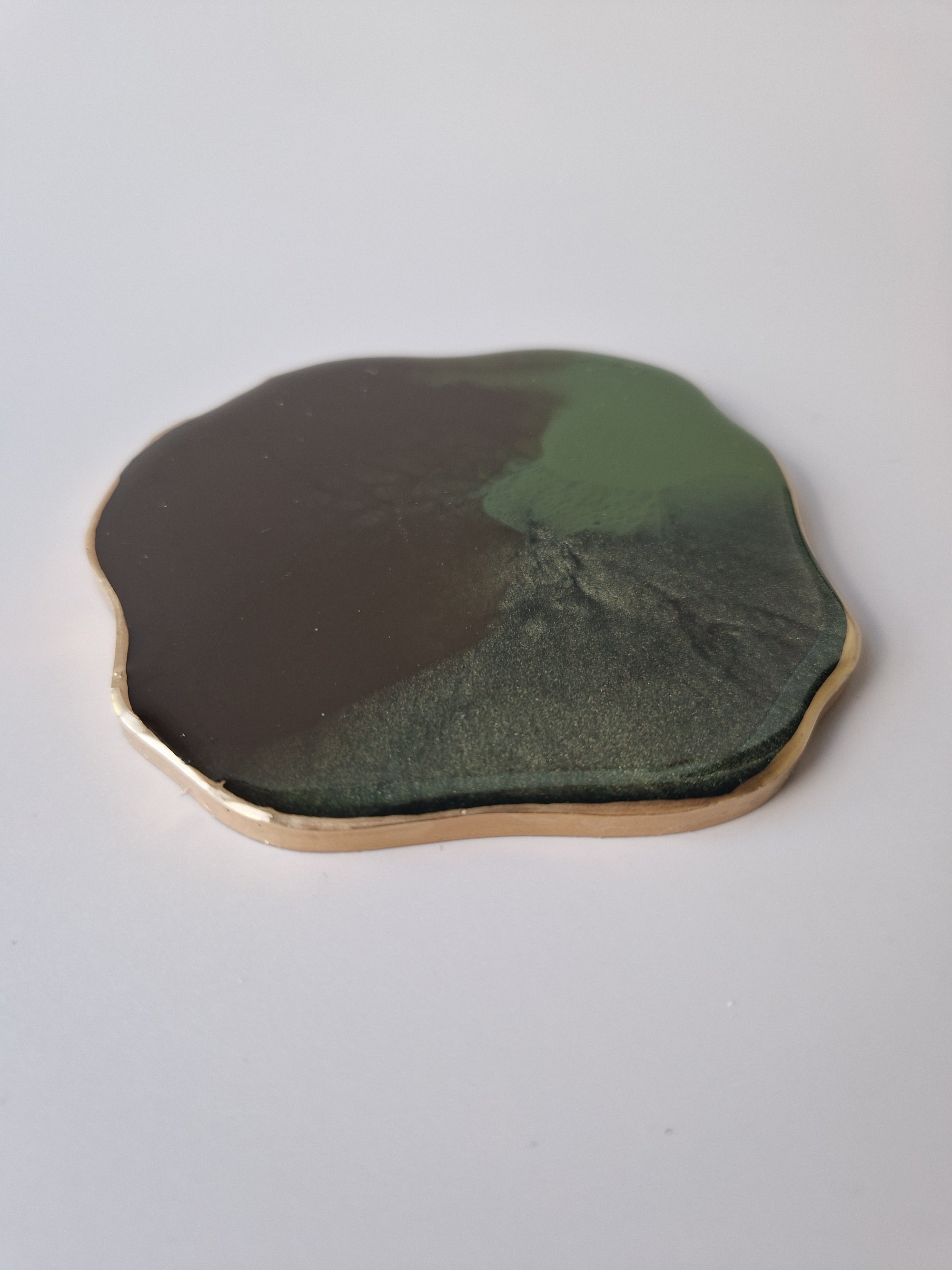 Detail van By Hand Onderzetter Earth, handgemaakt van epoxy in groen en bruin met goudkleurige rand – unieke ambachtelijke onderzetter.