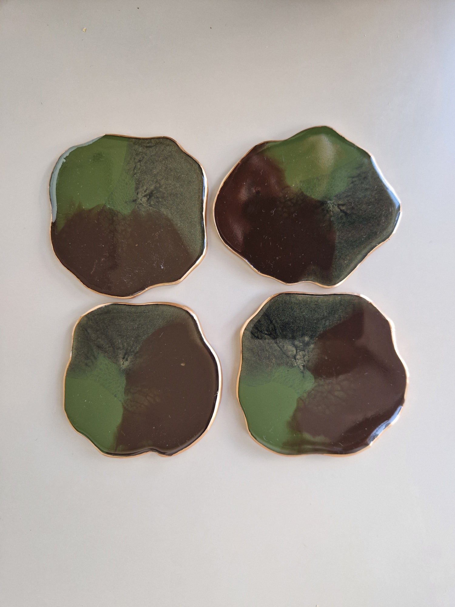 Set van vier By Hand onderzetters Earth, handgemaakt van epoxy in groen en bruin met goudkleurige rand – unieke interieuraccessoires