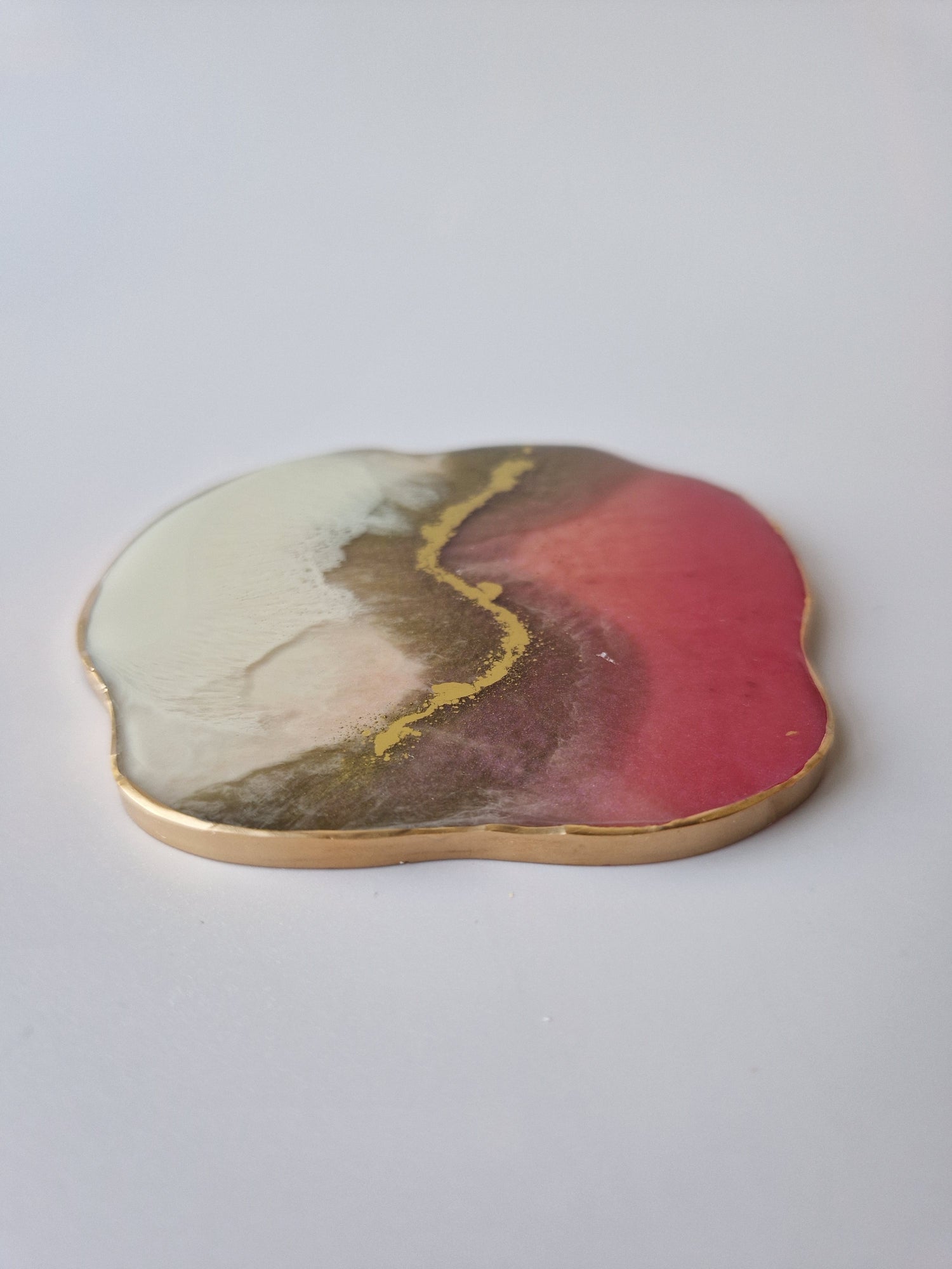 By Hand Onderzetter Tierra, handgemaakt van epoxy in wit, roze en bruin met goudaccent – unieke interieur onderzetter.