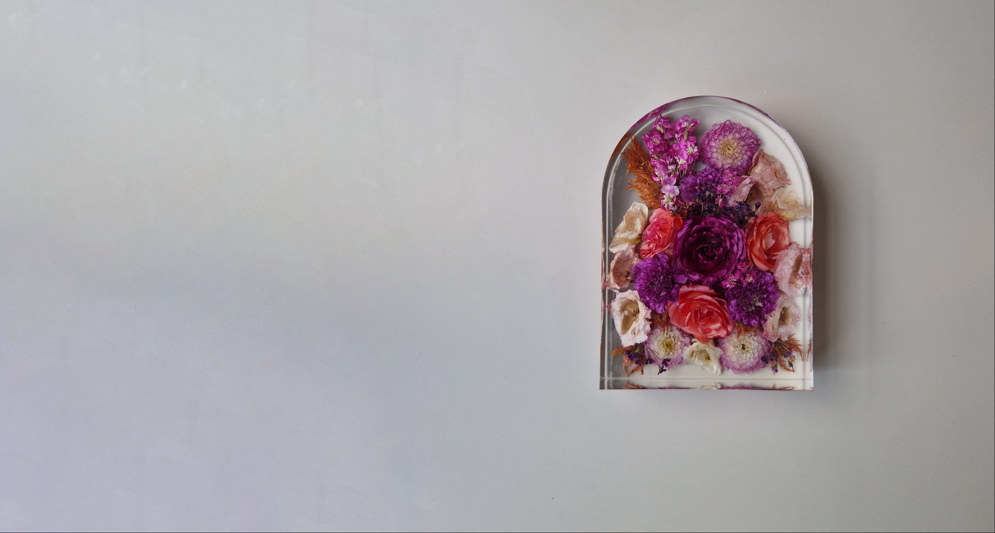 Epoxy Flower Shower in boogvorm met gedroogde paarse en roze bloemen tegen een rustige lichte achtergrond.