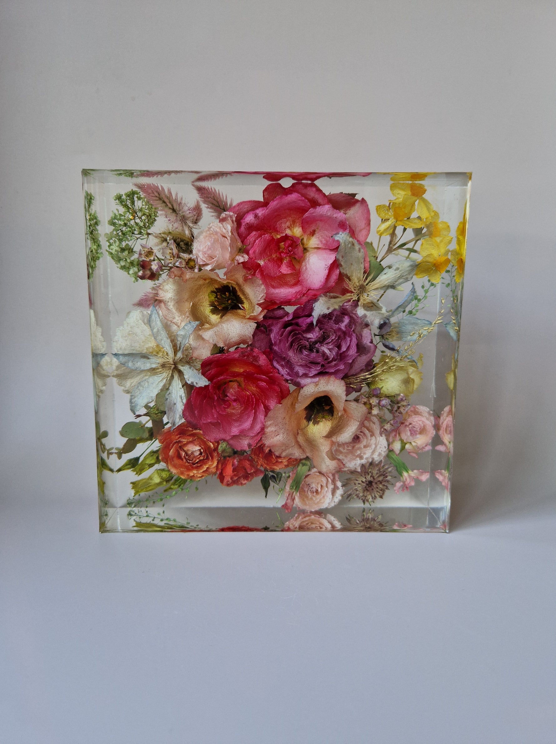 Vierkante epoxy Flower Shower met gedroogde roze, paarse en gele bloemen op een zachte, neutrale achtergrond.