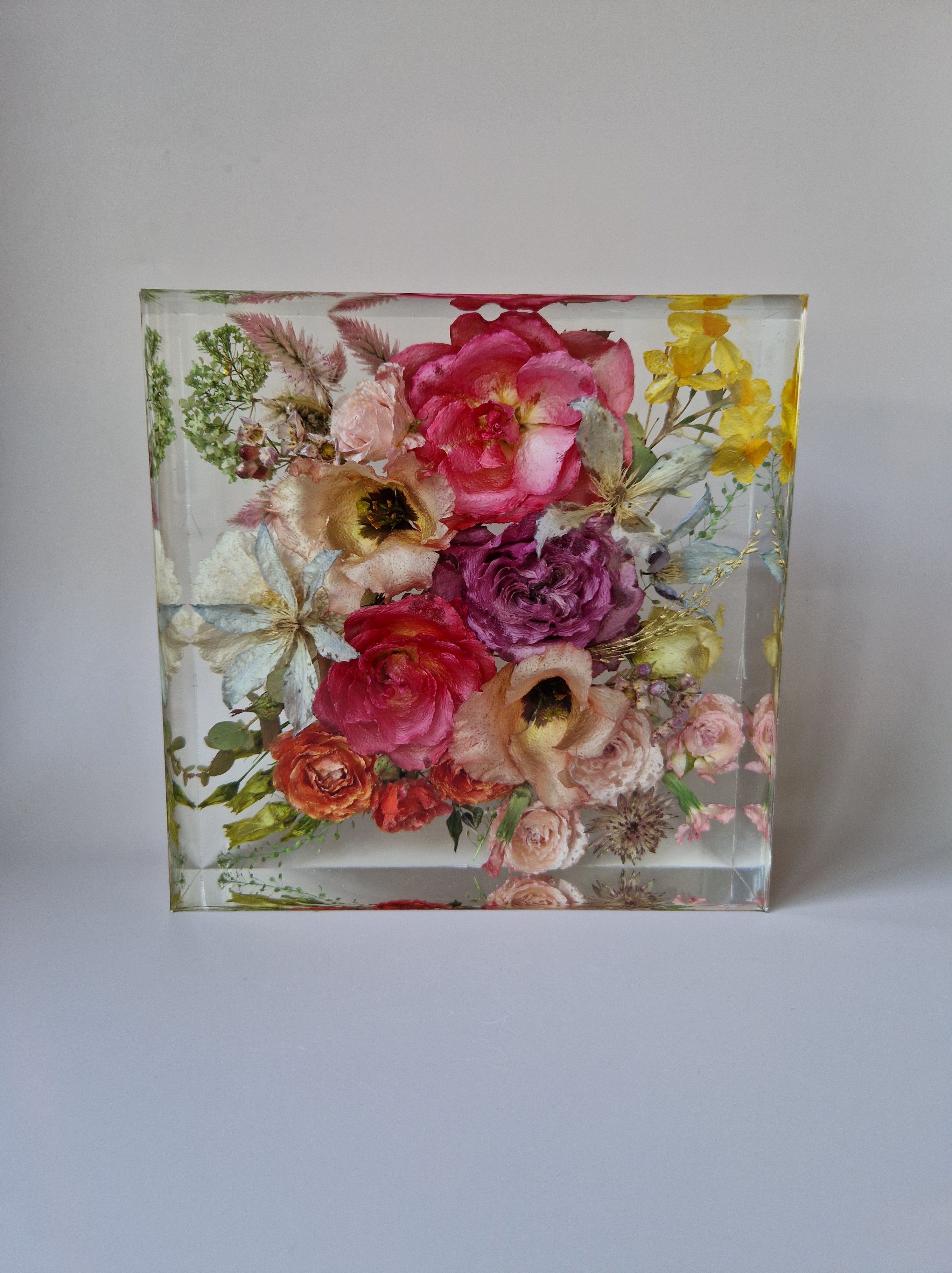 Vierkante epoxy Flower Shower met gedroogde roze, paarse en gele bloemen op een zachte, neutrale achtergrond.